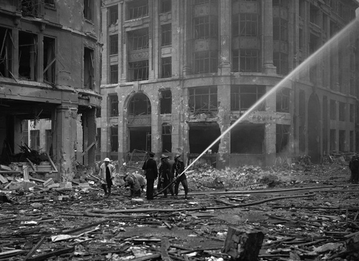 Firemen spray water on damaged buildings