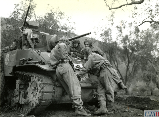 Four US tank crew soldiers study a map