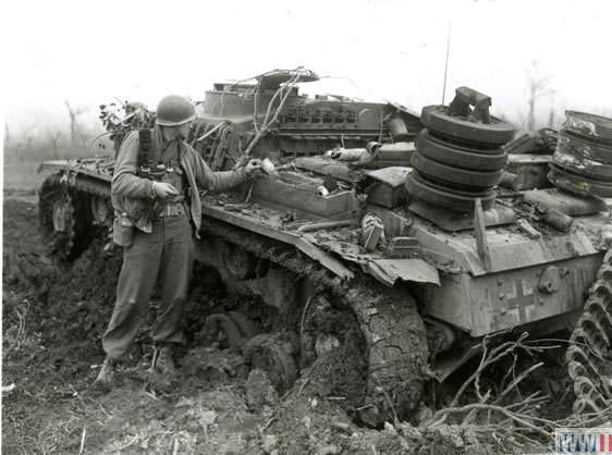 soldier examines a damaged German artillery weapon