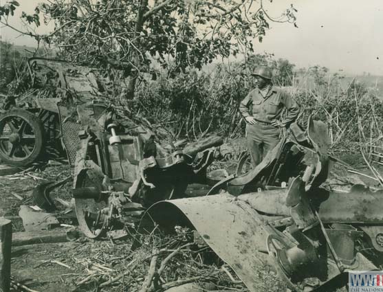 soldiers looks at destroyed German artillery