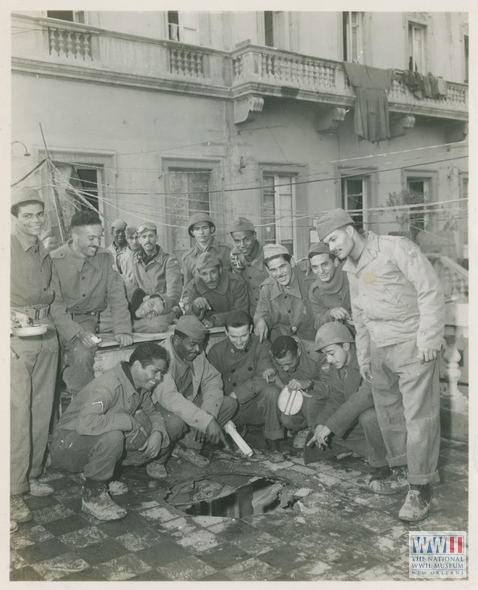 soldiers gather around shell hole