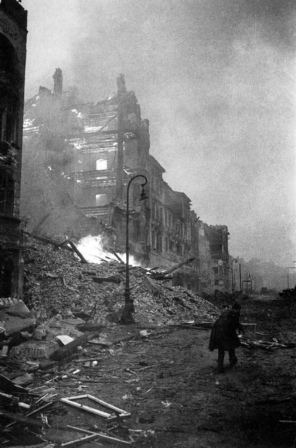 Soviet soldiers runs past a burning building in Berlin